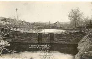 photo of old dam with bridge in background